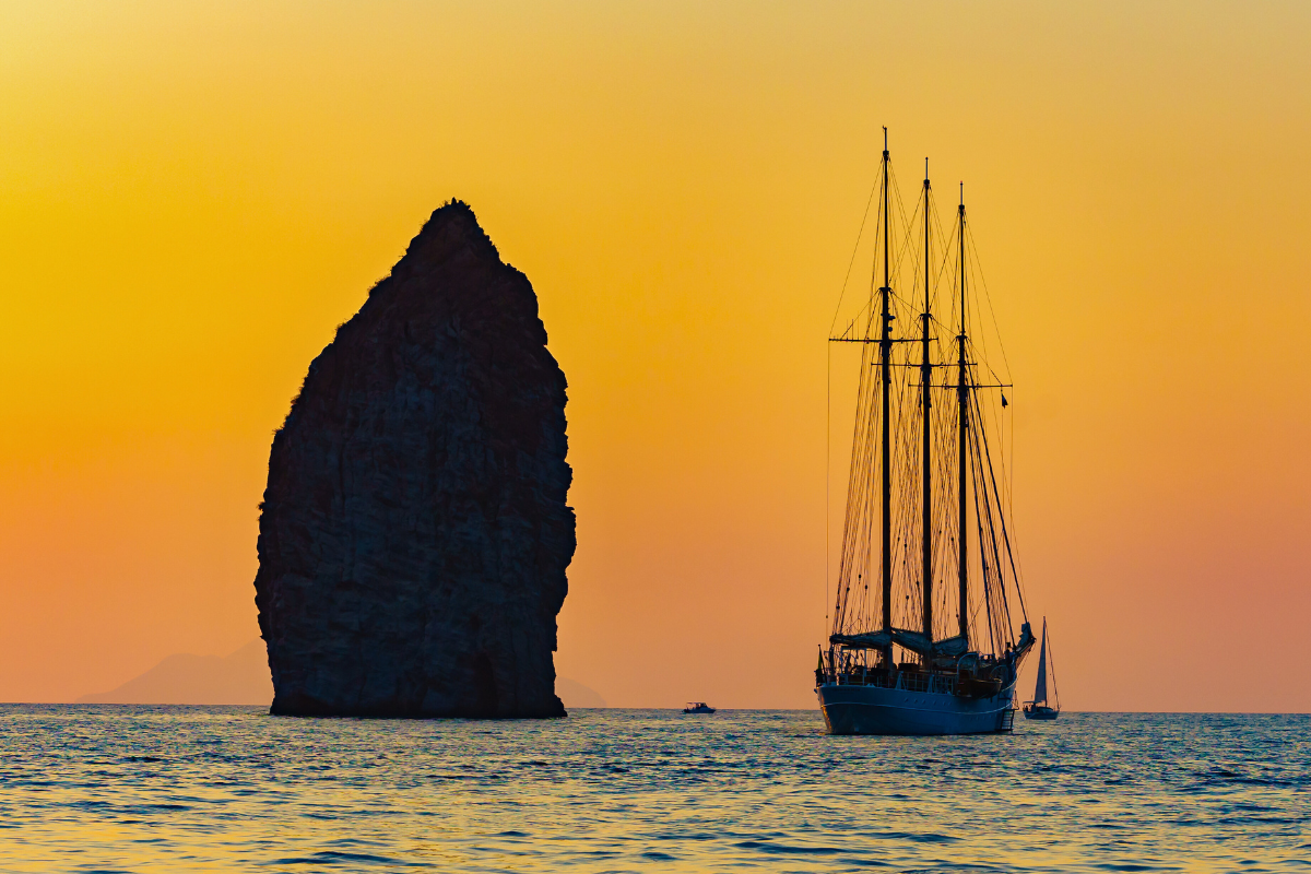Veliero al tramonto davanti allo scoglio di Strombolicchio nelle Isole Eolie, Sicilia