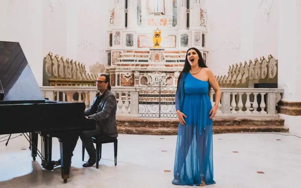 Esibizione musicale con cantante lirica e pianista Carmelo Travia durante un concerto al Festival EOLIÈ nelle Isole Eolie, dedicato ad arte, letteratura e società.