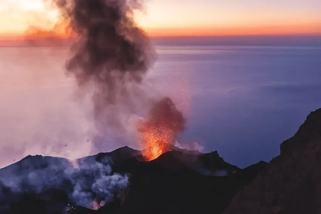 Eruzione del vulcano Stromboli con vista sul mare al tramonto, Isole Eolie