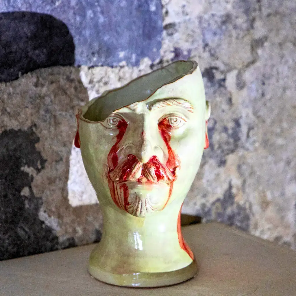 Scultura in ceramica “Piramo” di Nicolò Morales, testa maschile spezzata con dettagli rossi, esposta al Festival EOLIé25 alle Isole Eolie.