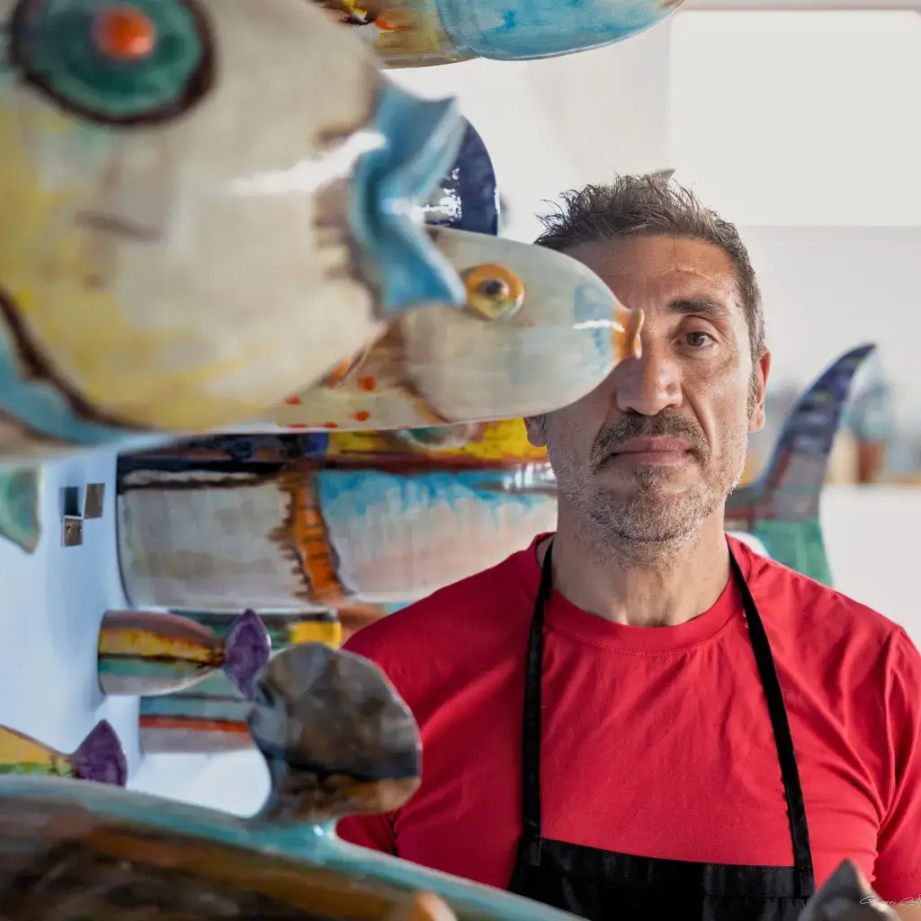 Ritratto di Nicolò Morales nel suo laboratorio di ceramica, circondato dalle sue opere colorate, realizzato per il Festival EOLIé25.